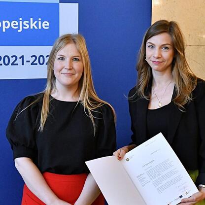 Joanna Bojczuk i Rafał Adamczyk wręczają listy gratulacyjne w ramach programu Funduszy Europejskich dla Śląska 2021-2027. (wygenerowano przez AI)