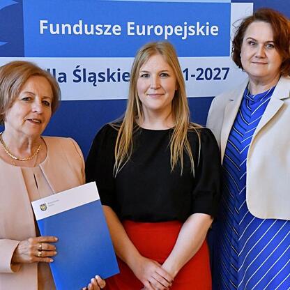 Trzy kobiety przedstawiają projekt Funduszy Europejskich dla Śląska 2021-2027. (wygenerowano przez AI)