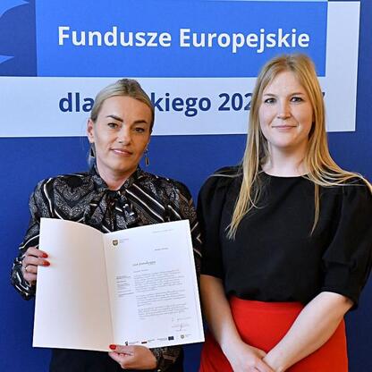 Joanna Bojczuk i Rafał Adamczyk wręczają listy gratulacyjne beneficjentom projektów edukacyjnych w ramach Funduszy Europejskich dla Śląska 2021-2027. (wygenerowano przez AI)