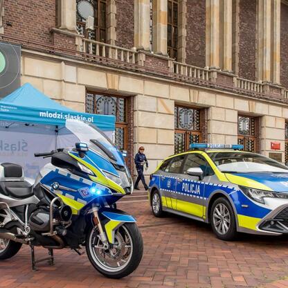 Na zdjęciu widoczne są motocykl i samochód policyjny przed namiotem z logo 