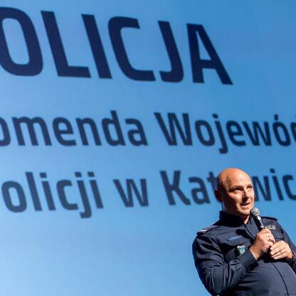 Policejny inspektor przemawia na konferencji o bezpieczeństwie drogowym i edukacji dla młodzieży. (wygenerowano przez AI)
