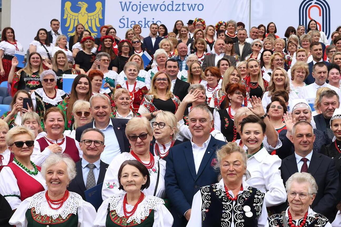 Grupa ludzi w tradycyjnych strojach na Stadionie Śląskim podczas uroczystości wsparcia dla kół gospodyń wiejskich. (wygenerowano przez AI)