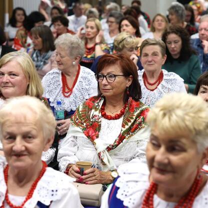Grupa kobiet w tradycyjnych strojach regionalnych uczestniczy w konferencji w Stadionie Śląskim. (wygenerowano przez AI)
