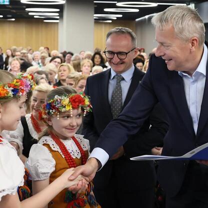 Wicemarszałek Grzegorz Boski i Marszałek Wojciech Saługa spotykają się z dziećmi w tradycyjnych strojach na Stadionie Śląskim. (wygenerowano przez AI)