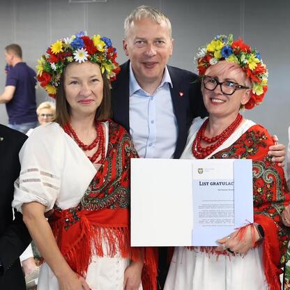 Grupa ludzi w tradycyjnych strojach na Stadionie Śląskim podczas uroczystości wsparcia dla kół gospodyń wiejskich. (wygenerowano przez AI)