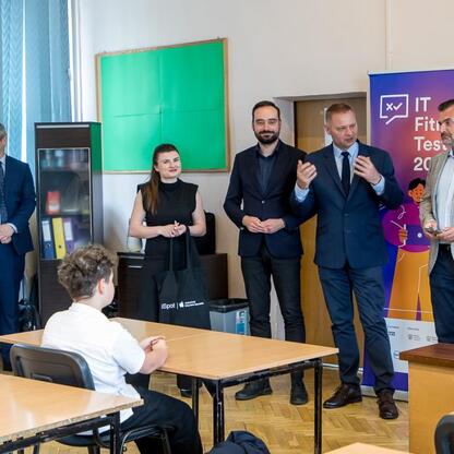 Grupa dorosłych i dzieci w klasie podczas IT Fitness Test 2024, z udziałem Rafała Adamczyka, wiceprezydenta Sosnowca. (wygenerowano przez AI)