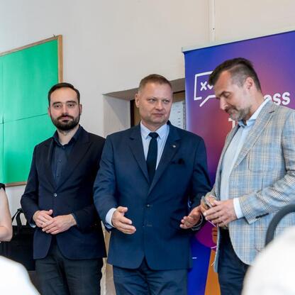 Trzech mężczyzn w strojach formalnych uczestniczy w IT Fitness Test, organizowanym przez Związek Cyfrowa Polska, podczas wydarzenia wojewódzkiego. (wygenerowano przez AI)