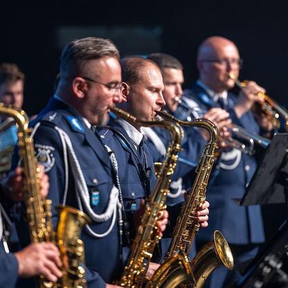 Na scenie grają muzyka w mundurach, wspierając kampanię o bezpieczeństwie i empatii. (wygenerowano przez AI)
