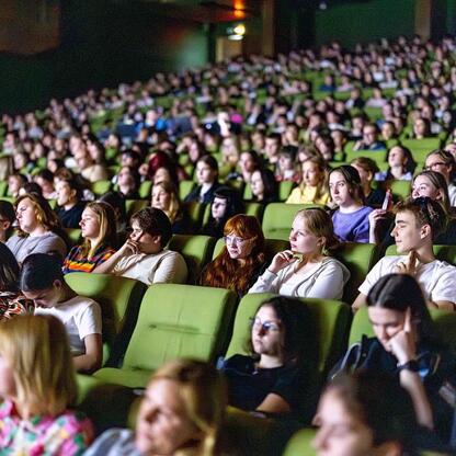 Audience in a theater-like setting attentively watching a presentation or performance. (wygenerowano przez AI)