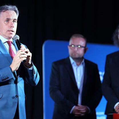 Mężczyzna w niebieskim garniturze prowadzi dyskusję podczas panelu w ramach 
