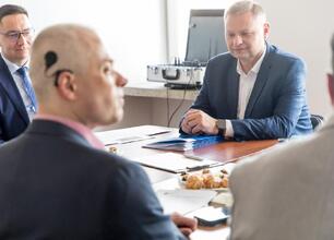 Rafał Adamczyk (Członek Zarządu Województwa) przekazuje dokument osobie z niepełnosprawnością podczas posiedzenia Wojewódzkiej Społecznej Rady ds. Osób Niepełnosprawnych. (wygenerowano przez AI)