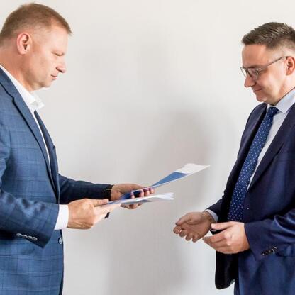 Rafał Adamczyk (Członek Zarządu Województwa) przekazuje dokumenty podczas posiedzenia Silesia Social Council for People with Disabilities. (wygenerowano przez AI)