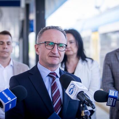 Wicemarszałek Województwa Śląskiego Grzegorz Boski przemawia na konferencji prasowej o nowych połączeniach kolejowych między Częstochową, Krakowem Płaszowem i Pyrzowicami. (wygenerowano przez AI)
