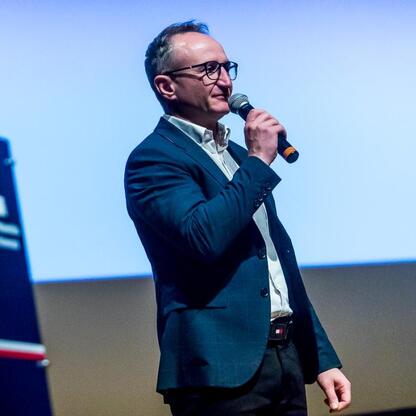 Grzegorz Boski, wicemarszałek Województwa Śląskiego, przemawia na konferencji o bezpieczeństwie drogowym i hejcie wśród młodzieży. (wygenerowano przez AI)