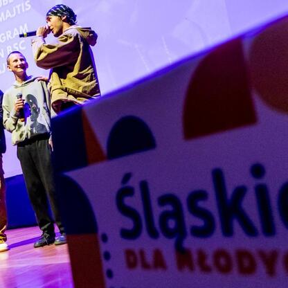 Na scenie w Częstochowie trwa spotkanie z wicemarszałkiem Boskiem i zastępcą prezydenta Pabiś, promujące bezpieczeństwo drogowe i walkę z cyberbullyingiem. (wygenerowano przez AI)