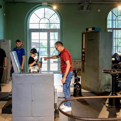 Grupa turystów eksploruje historyczny przemysłowy teren, uczestnicząc w festiwalu INDUSTRIADA, który uczcił dziedzictwo przemysłowe Śląska. (wygenerowano przez AI)