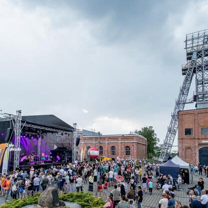 Widoczna jest scena festiwalowa w Carnall Sztolni Królowa Luiza w Zabrzu, gdzie odbywa się INDUSTRIADY, festiwal upamiętniający przemysłowe dziedzictwo regionu. (wygenerowano przez AI)