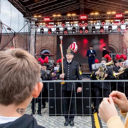 Widoczna scena z festiwalu INDUSTRIADY, z koncertem i widowiskiem przedstawiającym przemysłowe dziedzictwo Śląska. (wygenerowano przez AI)