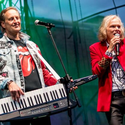 Fotografia przedstawiająca koncert na festiwalu INDUSTRIADY w Silesia, z muzykami grającymi na keyboardzie i śpiewającymi. (wygenerowano przez AI)