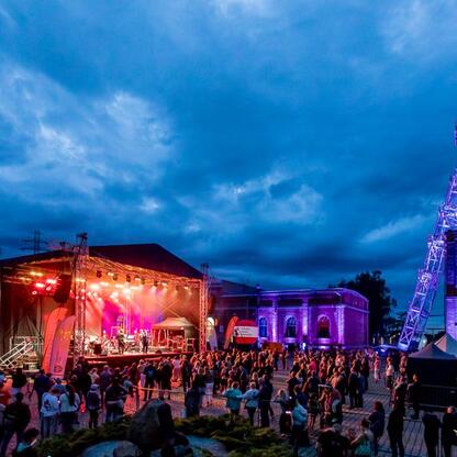 Widoczna jest scena festiwalowa z koncertem na Carnall Sztolni Królowa Luiza w Zabrzu, podświetlona kolorowymi światłami. (wygenerowano przez AI)