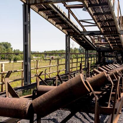 Abandoned industrial site, likely former coal mine, with rusted metal structures and pipes, showing signs of disrepair and neglect. (wygenerowano przez AI)
