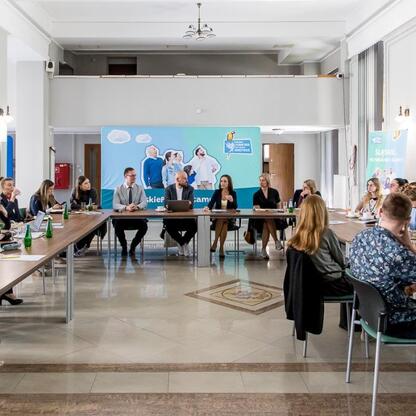 Widoczna jest sesja dyskusyjna w konferencyjnym pomieszczeniu, gdzie uczestnicy omawiają plany adaptacji do zmian klimatu dla województwa śląskiego. (wygenerowano przez AI)