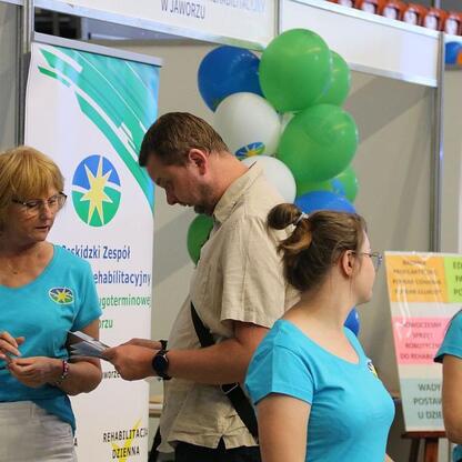 Na II Dniach Zdrowia w Bielsku-Białej uczestnicy wymieniają informacje na stoisku rehabilitacyjnym. (wygenerowano przez AI)