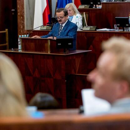 Formalna sesja Sejmiku Województwa Śląskiego, gdzie marszałek Wojciech Saługa przemawia do radnych. (wygenerowano przez AI)