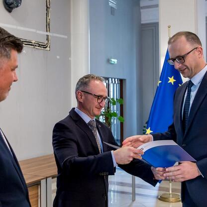 Wicemarszałek Grzegorz Boski wręcza listy gratulacyjne beneficjentom projektów energetycznych finansowanych z Unii Europejskiej. (wygenerowano przez AI)