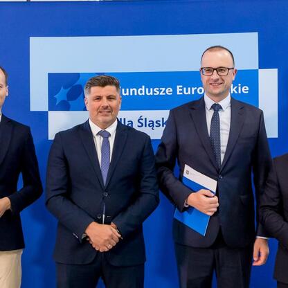 Wicemarszałek Grzegorz Boski i jego współpracownicy przedstawiają beneficjentom listy gratulacyjne w ramach projektu Fundusze Europejskie dla Śląska 2021-2027. (wygenerowano przez AI)