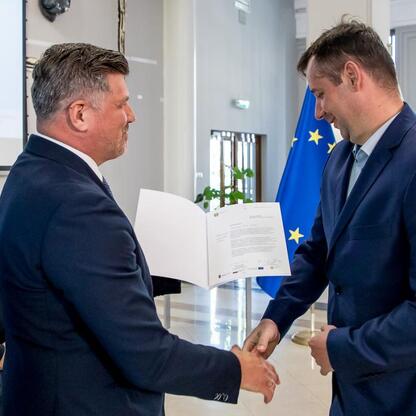 Grzegorz Boski, wicemarszałek Województwa Śląskiego, wręcza listy gratulacyjne beneficjentom konkursów związanych z rozwojem energetyki i efektywnością budynków użyteczności publicznej. (wygenerowano przez AI)