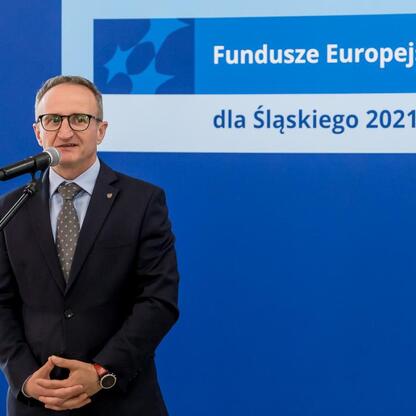 Wicemarszałek Województwa Śląskiego Grzegorz Boski przemawia na podium podczas uroczystości związanych z Funduszami Europejskimi dla Śląska 2021-2027. (wygenerowano przez AI)