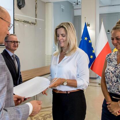 Wicemarszałek Grzegorz Boski wręcza listy gratulacyjne beneficjentom projektów energetycznych finansowanych z Unii Europejskiej. (wygenerowano przez AI)