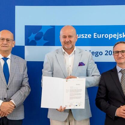 Wicemarszałek Grzegorz Boski i dwaj goście na ceremonii wręczenia nagród dla beneficjentów projektów energetycznych województwa śląskiego. (wygenerowano przez AI)
