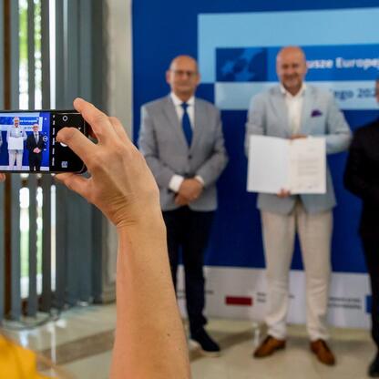 Wicemarszałek Grzegorz Boski wręcza listy gratulacyjne beneficjentom projektów energetycznych w Województwie Śląskim. (wygenerowano przez AI)