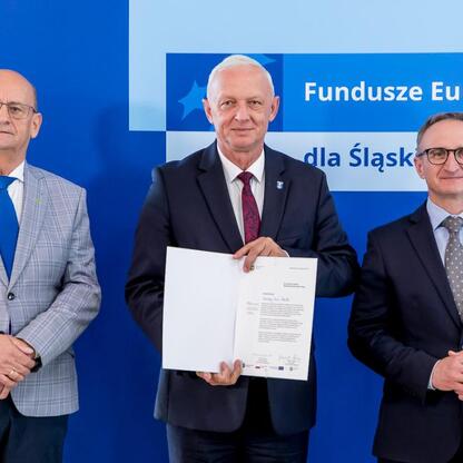 Wicemarszałek Grzegorz Boski i jego współpracownicy prezentują beneficjentom listy gratulacyjne w ramach projektu Funduszy Europejskich dla Śląska 2021-2027. (wygenerowano przez AI)