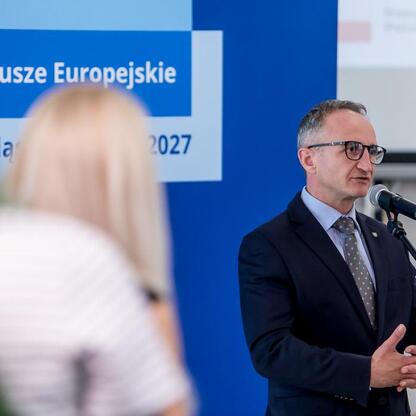 Grzegorz Boski, Wicemarszałek Województwa Śląskiego, przemawia na podium podczas uroczystości związanych z Funduszami Europejskimi. (wygenerowano przez AI)
