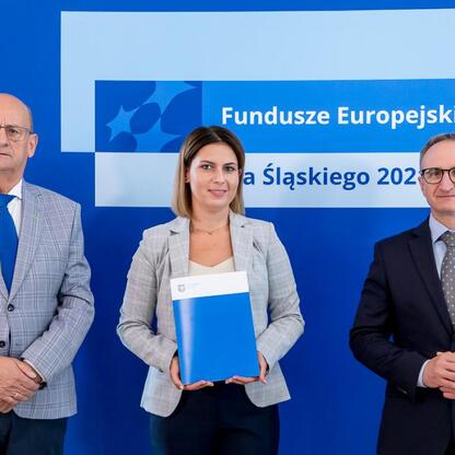 Wicemarszałek Grzegorz Boski i dwaj jego współpracownicy przedstawiają listy gratulacyjne dla beneficjentów projektów europejskich wspierających efektywność energetyczną w Śląsku. (wygenerowano przez AI)