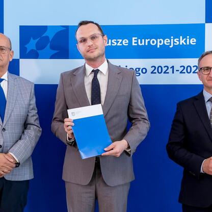 Wicemarszałek Grzegorz Boski i jego współpracownicy prezentują beneficjentom funduszy europejskich certyfikaty za projekty zrównoważonej energetyki w Śląsku. (wygenerowano przez AI)