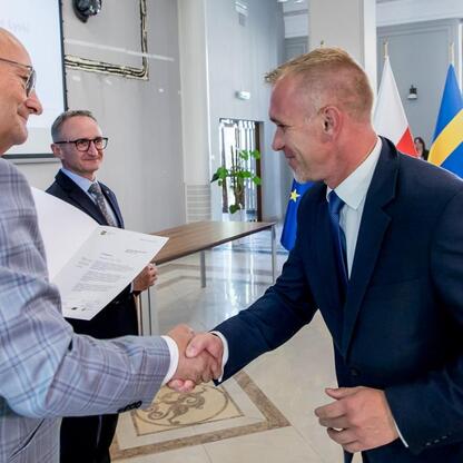 Wicemarszałek Grzegorz Boski wręcza listy gratulacyjne beneficjentom konkursów związanych z rozwojem energetyki województwa śląskiego. (wygenerowano przez AI)