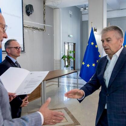 Wicemarszałek Grzegorz Boski wręcza listy gratulacyjne beneficjentom projektów energetycznych w Województwie Śląskim. (wygenerowano przez AI)