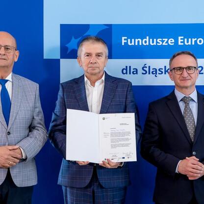 Wicemarszałek Grzegorz Boski wręcza listy gratulacyjne beneficjentom konkursów związanych z rozwojem energetyki i efektywnością budynków użyteczności publicznej w ramach Funduszy Europejskich dla Śląs (wygenerowano przez AI)