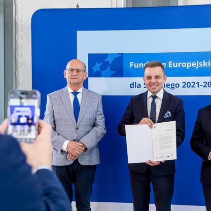 Grzegorz Boski, wicemarszałek Województwa Śląskiego, wręcza listy gratulacyjne beneficjentom konkursów związanych z rozwojem energetyki i efektywnością budynków użyteczności publicznej. (wygenerowano przez AI)