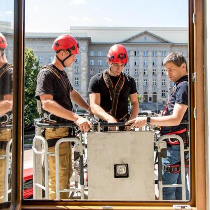 Zdjęcie przedstawia grupę osób w mundurach i sprzęcie ratowniczym podczas ćwiczeń ewakuacyjnych w Urzędzie Marszałkowskim Województwa Śląskiego w Katowicach. (wygenerowano przez AI)