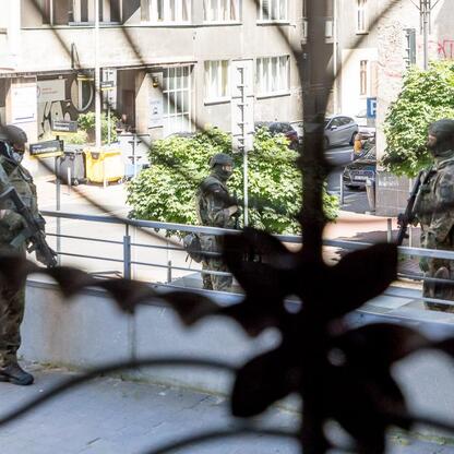 Trzy żołnierze w mundurach i hełmach stoją na chodniku przed gmachem Urzędu Marszałkowskiego Województwa Śląskiego. (wygenerowano przez AI)