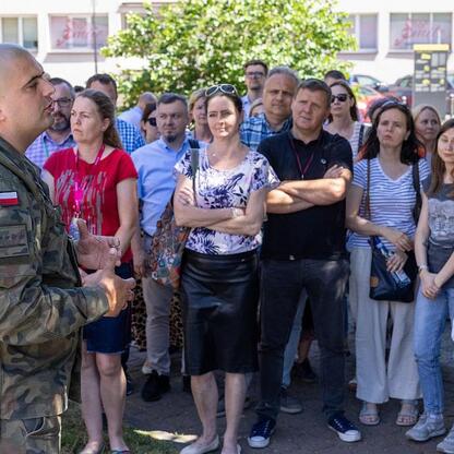 Grupa ludzi na ćwiczeniach ewakuacyjnych przed Urzędem Marszałkowskim Województwa Śląskiego. (wygenerowano przez AI)