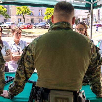 Zebrała się grupa osób w mundurach i w cywilu, omawiająca procedury ewakuacyjne przed gmachem Urzędu Marszałkowskiego Województwa Śląskiego. (wygenerowano przez AI)