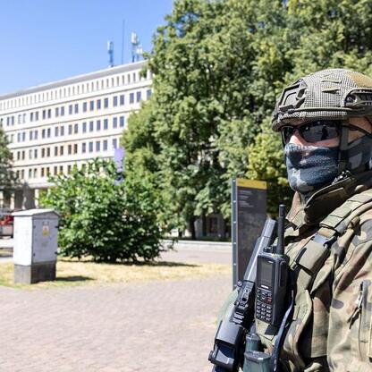 Zdjęcie przedstawia żołnierza w pełnym uzbrojeniu przed gmachem Urzędu Marszałkowskiego Województwa Śląskiego. (wygenerowano przez AI)