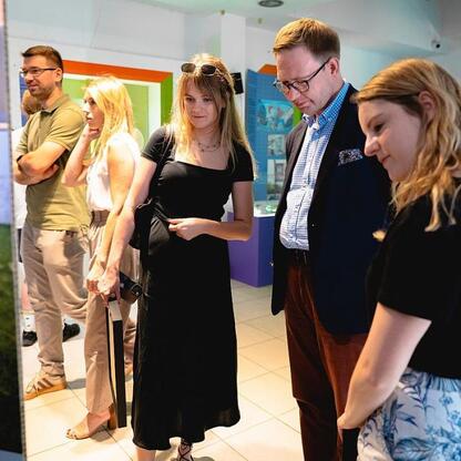 Grupa osób uczestniczących w jubileuszowej gali Śląskiej Rzeczy, zgromadzona w otoczeniu wystaw i paneli informacyjnych. (wygenerowano przez AI)