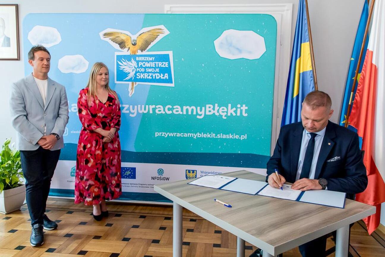 Joanna Bojczuk podpisuje dokumenty w Urzędzie Marszałkowskim Województwa Śląskiego, związany z realizacją kampanii edukacyjno-informacyjnej "Bierzemy powietrze pod swoje skrzydła". (wygenerowano przez AI)